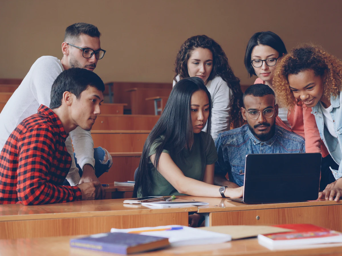 A group of students gathered around a laptop